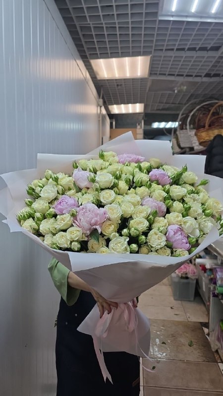 Флорист держит огромный белый букет из роз